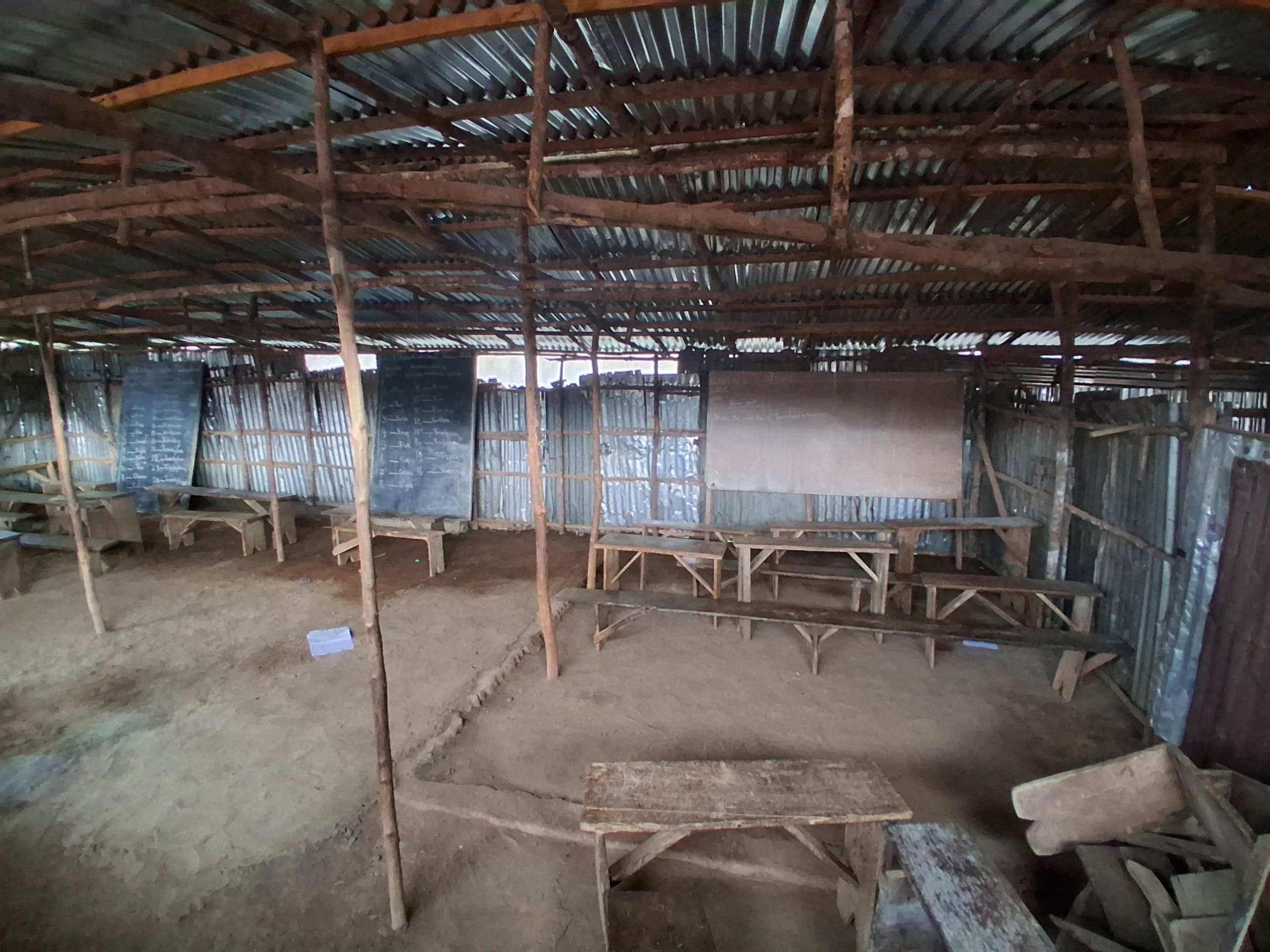 Inside Evangelica Missionary Primary School — wooden benches and dirt floor